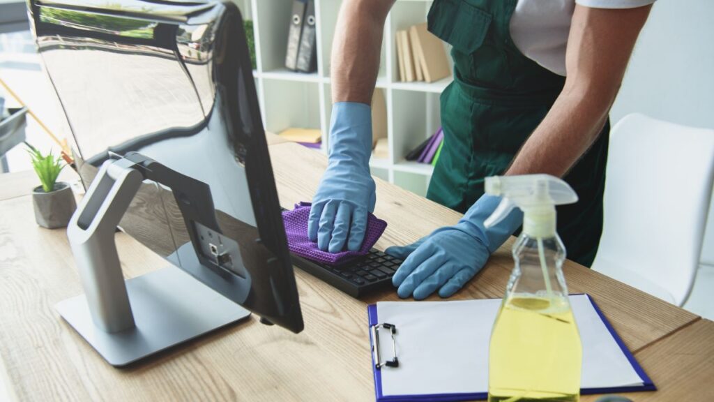 A professional cleaner sanitizing an office workspace, demonstrating the importance of professional cleaning services.